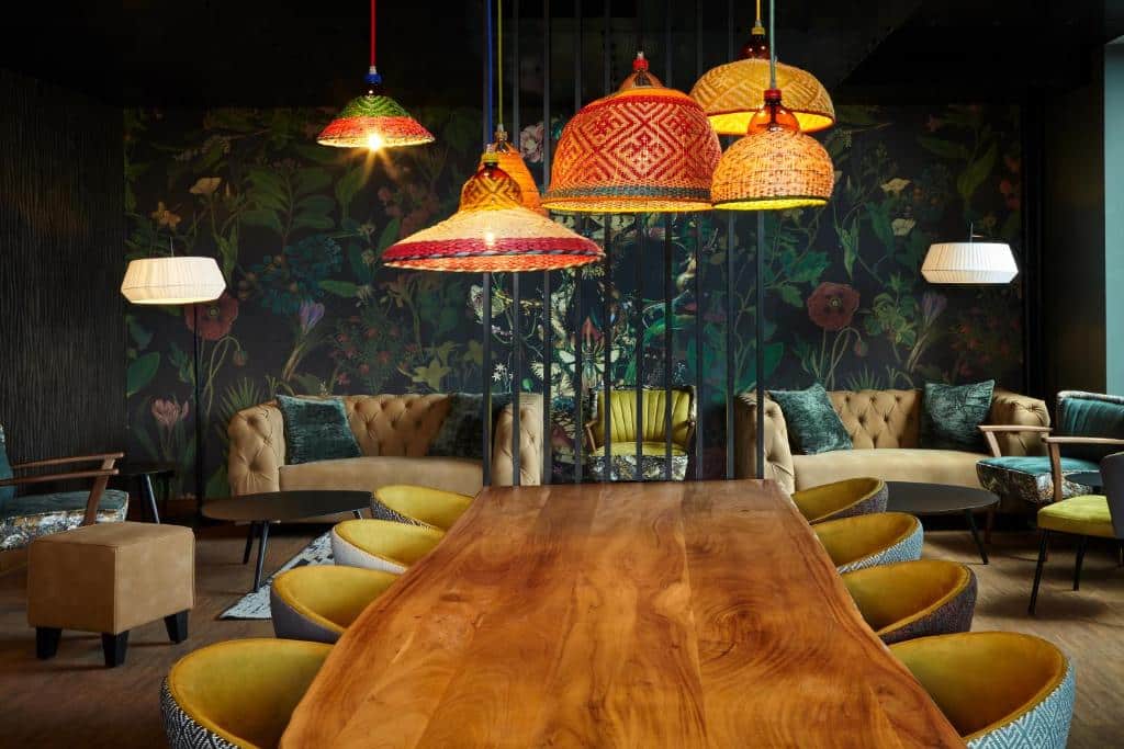 Lounge im Reverb by Hard Rock Hotel im Hamburg Bunker mit Sitzgelegenheiten, dunkler Tapete mit Blumenmuster und bunten Lampenschirmen.