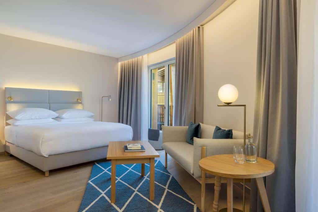 Doppelzimmer im Caro & Selig mit einem Doppelbett, Sofa, Couchtisch und Balkon.